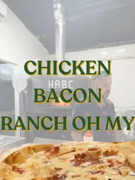 "Chicken Bacon Ranch pizza in Bridge City with crispy bacon, melted cheese, and a wood-fired brick oven background."
