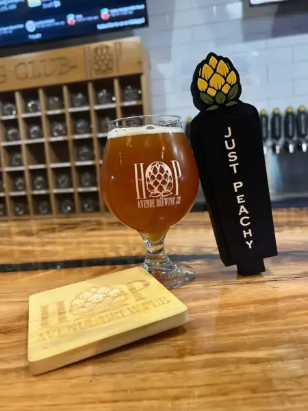 "A fresh pour of Just Peachy wheat beer in a branded glass at Hop Avenue Brew Pub in Bridge City."