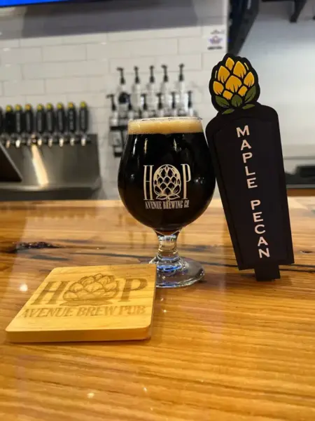 "Maple Pecan Smoked Porter in a branded snifter glass next to its tap handle at Hop Avenue Brew Pub in Bridge City