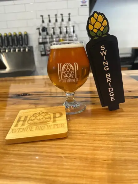 Swing Bridge Vanilla Imperial Cream Ale in a branded glass next to its tap handle at Hop Avenue Brew Pub in Bridge City.