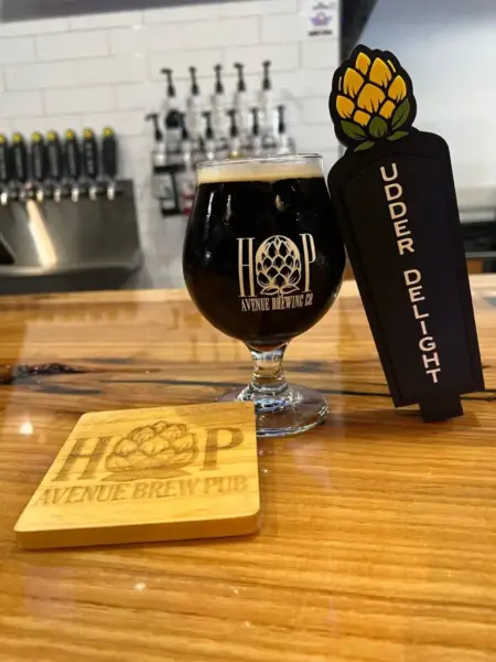 "A dark pour of Udder Delight milk stout next to a custom tap handle at Hop Avenue Brew Pub in Bridge City."